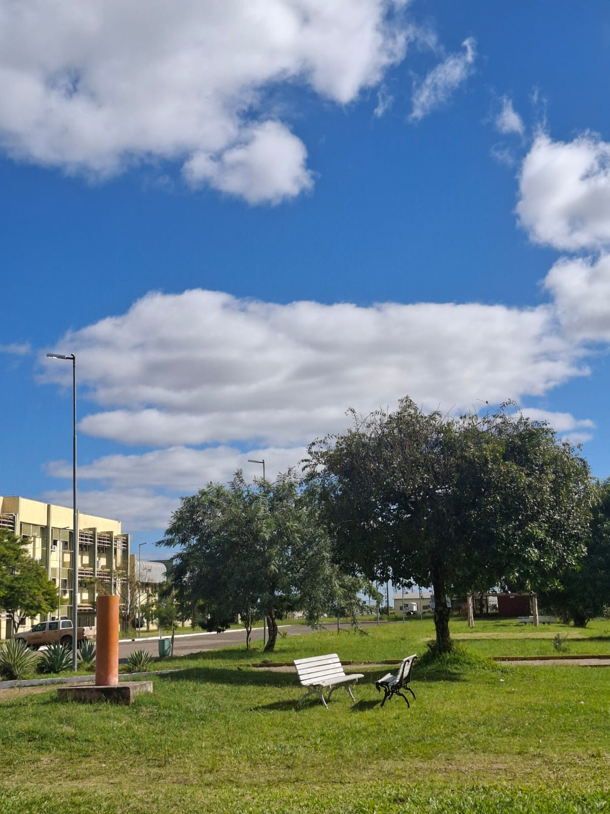 Área externa do Campus Itaqui da Universidade Federal do Pampa, com bancos, árvores, gramado e prédio ao fundo